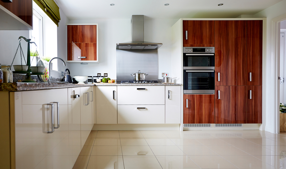 Spacious and modern modular kitchen interiors designed by Galaxy Interior Designers, featuring sleek white cabinetry, granite countertops, and warm wooden accents for a welcoming culinary space