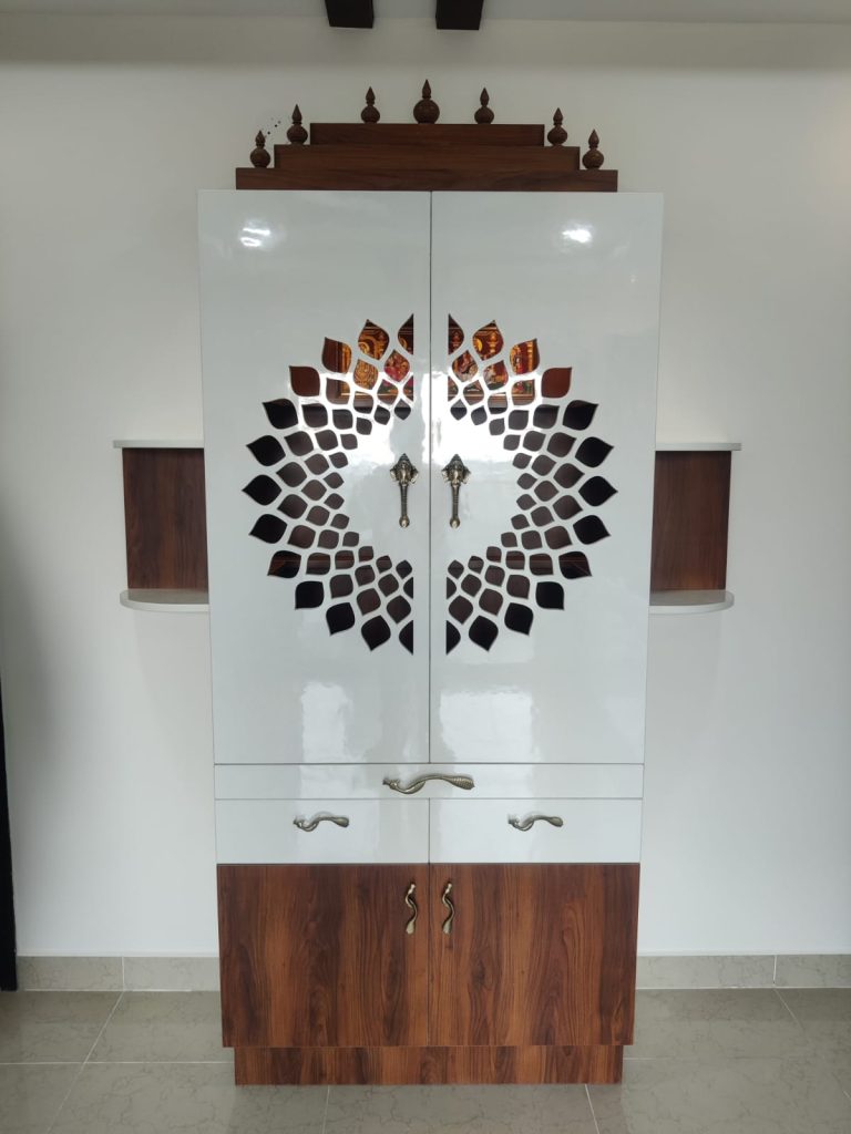 Elegant pooja room cabinet designed by Galaxy Interior Designers, Chennai, featuring a mix of glossy white and rich wooden
