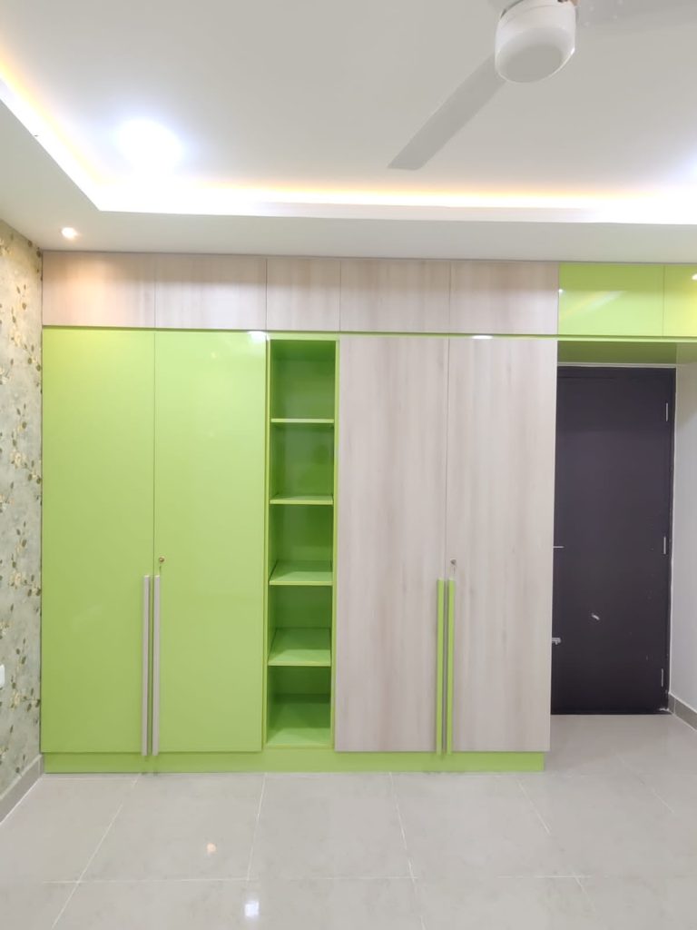 Contemporary and vibrant wardrobe with a mix of lime green and natural wood finishes, designed by Galaxy Interior Designers