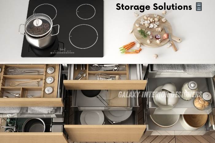 Top-down view of a modern kitchen with organized storage solutions, including neatly arranged utensils, pots, and plates in wooden drawers. Optimize your Chennai kitchen space with Galaxy Interior Designers' innovative storage solutions