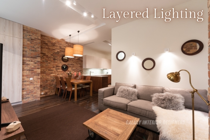 Layered lighting design by Galaxy Interior Designers in Chennai, featuring a modern living and dining area with a mix of pendant lights and wall sconces. Specializing in residential interiors that enhance ambiance through custom lighting solutions for homes and offices